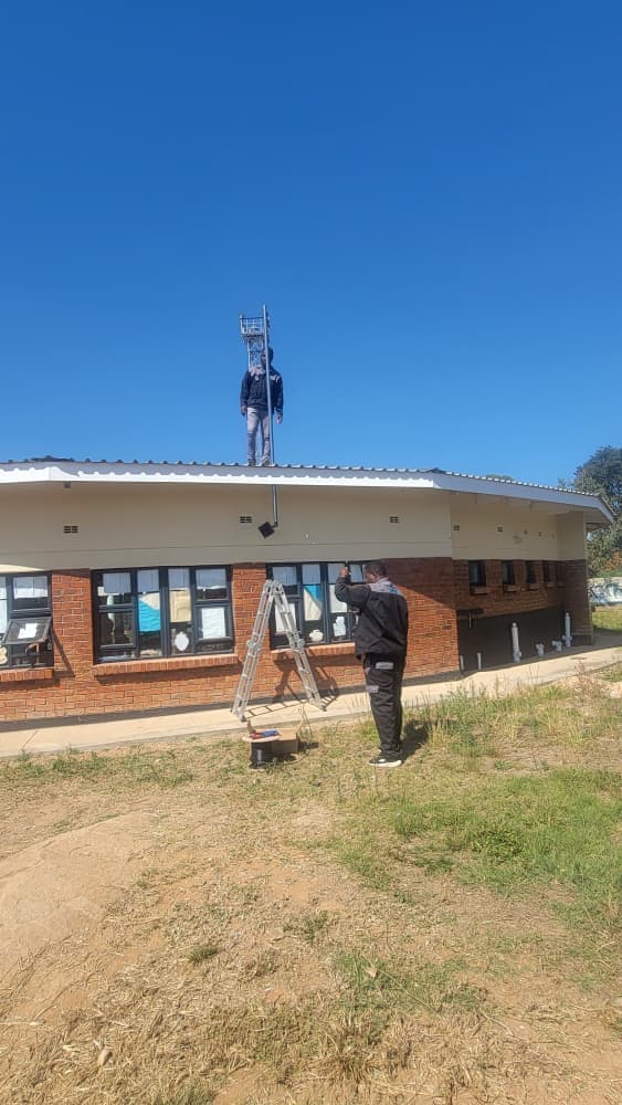 Technician installing antenna on building roof